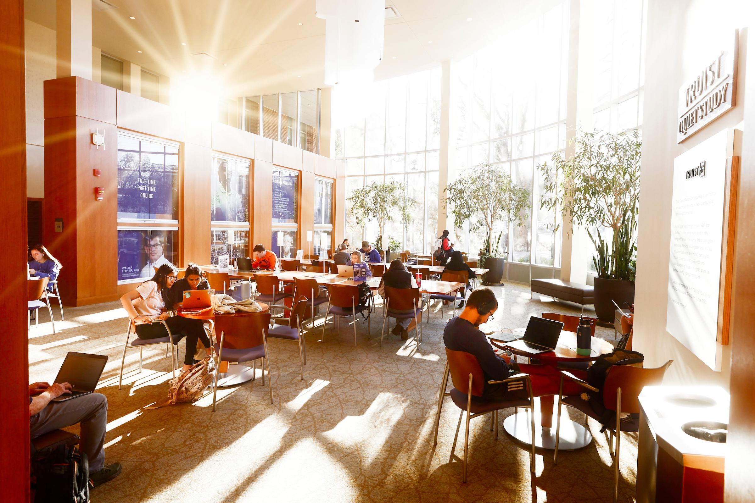 Sunlit front room of Gatton B&E filled with students studying at desks.