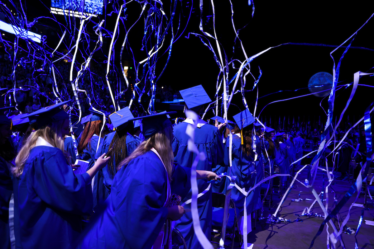 Blue and white streamers falling onto a crowd of students at commencement.