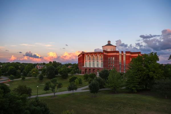 William T. Young Library bathed in sunset lighting with a dark blue sky and clouds on the horizon.