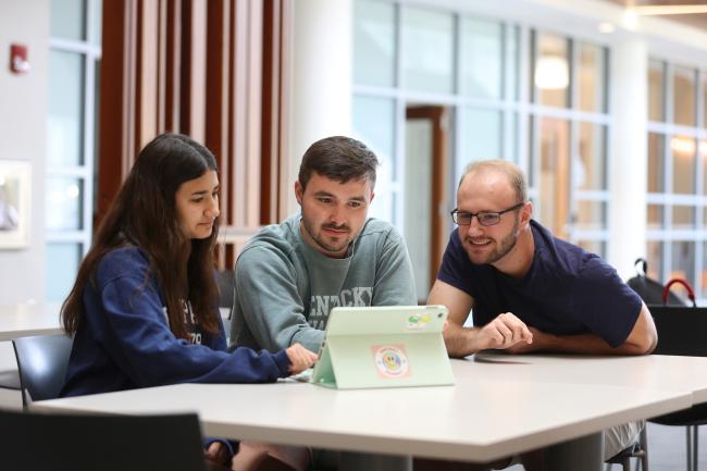 UK Pharmacy students working together and looking at an iPad.