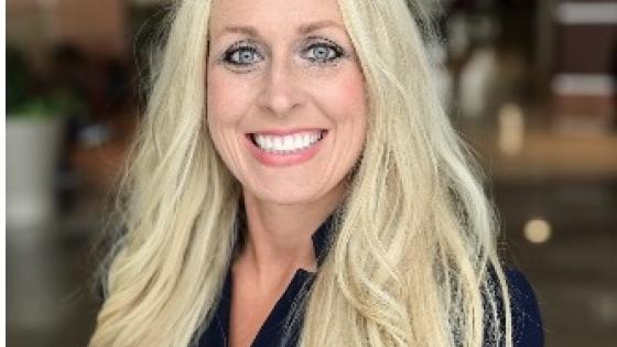 Headshot of woman with long, blonde hair wearing a navy button-up shirt. 