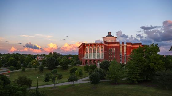 William T. Young Library bathed in sunset lighting with a dark blue sky and clouds on the horizon.