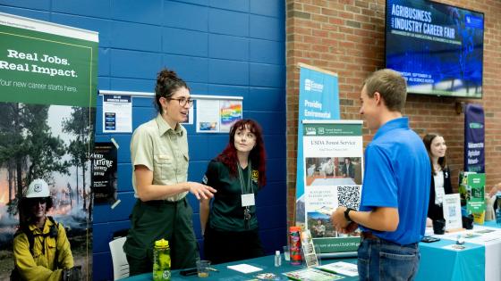 Student talks to recruiter at the USDA Forest Service Booth at a career fair.
