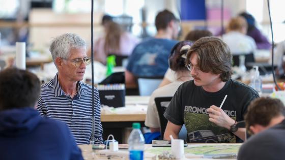 A student talking with the instructor in a design class with an iPad in front of them.