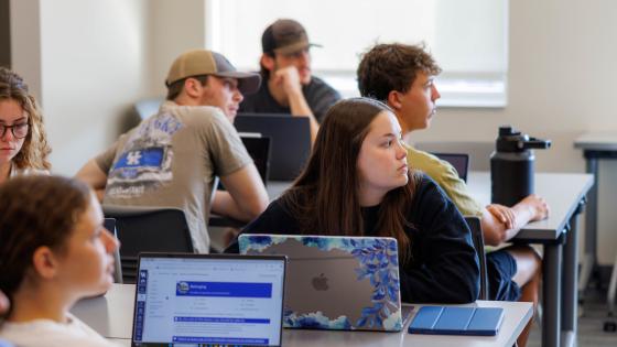 students sitting at tables in class looking at the instructor