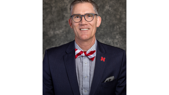 A portrait-style photo of Nick Pace wearing a navy blazer with a candy-cane-patterned bowtie and checkered dress shirt.