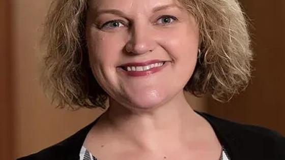 Headshot of Holly Hapke in a black cardigan and patterned shirt.