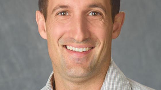Headshot of Nick Teets in a striped collared shirt.