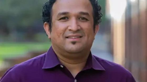Savio Poovathingal posing for a headshot while wearing a plum button down.