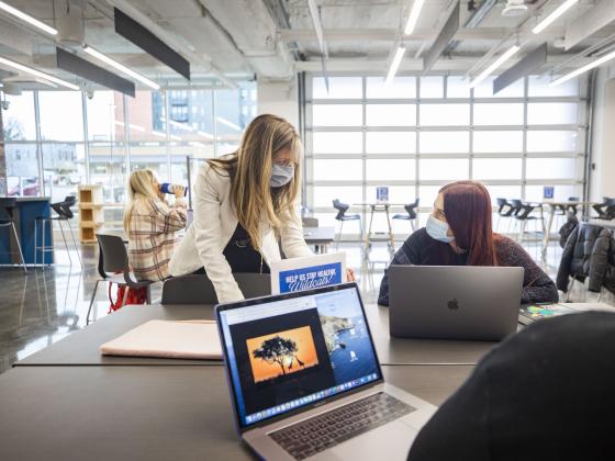 Photo of teacher teaching students with computers
