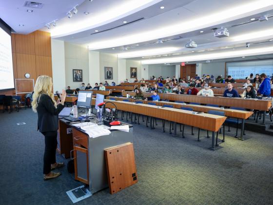 woman standing in front of large screen teaching class 