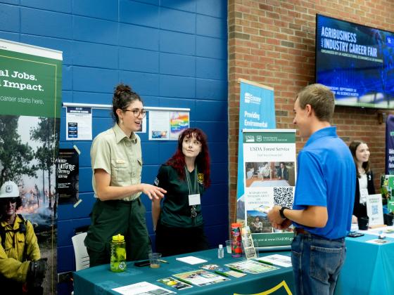 Student talks to recruiter at the USDA Forest Service Booth at a career fair.