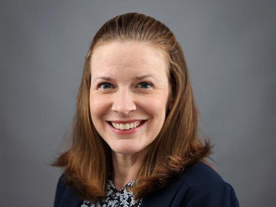 Brandi Frisby posing for a portrait wearing a navy blue cardigan.