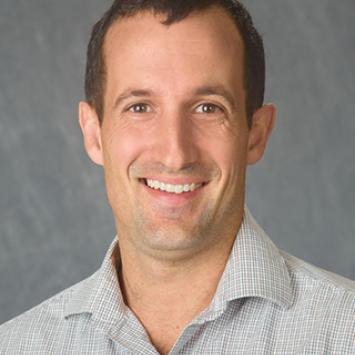 Headshot of Nick Teets in a striped collared shirt.