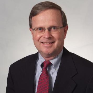 Headshot of Alfred Wiemann in a suit and red tie.