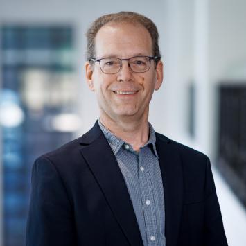 Steve Rankin posing for a headshot wearing a blue button down shirt and dark blue blazer