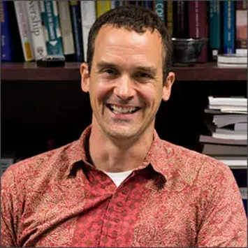 Headshot of Rick Ingram in a red-orange collared shirt.