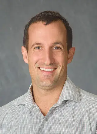 Headshot of Nick Teets in a striped collared shirt.