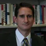 Headshot of Steve Voss in a suit in front of a bookshelf.