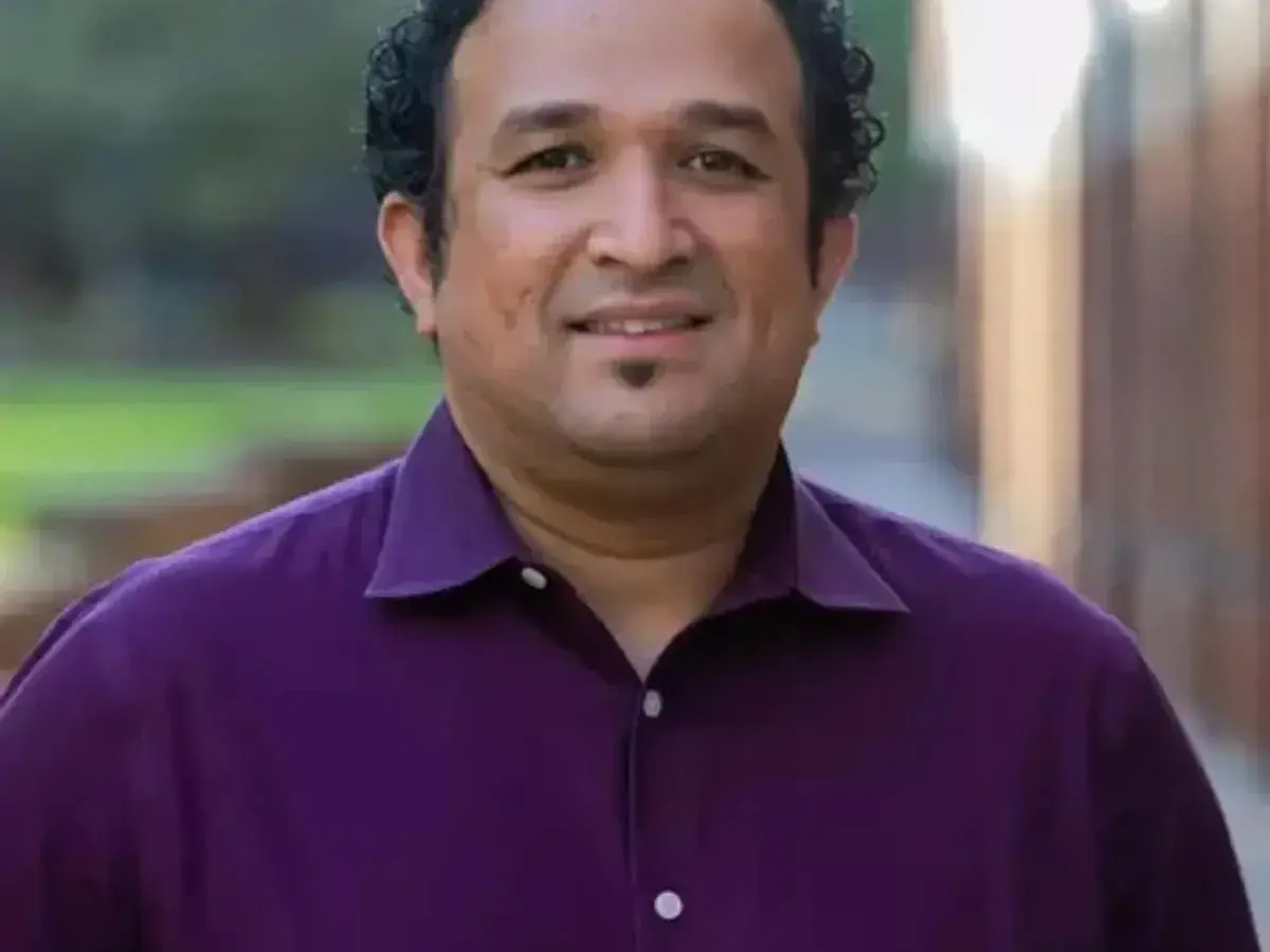 Savio Poovathingal posing for a headshot while wearing a plum button down.