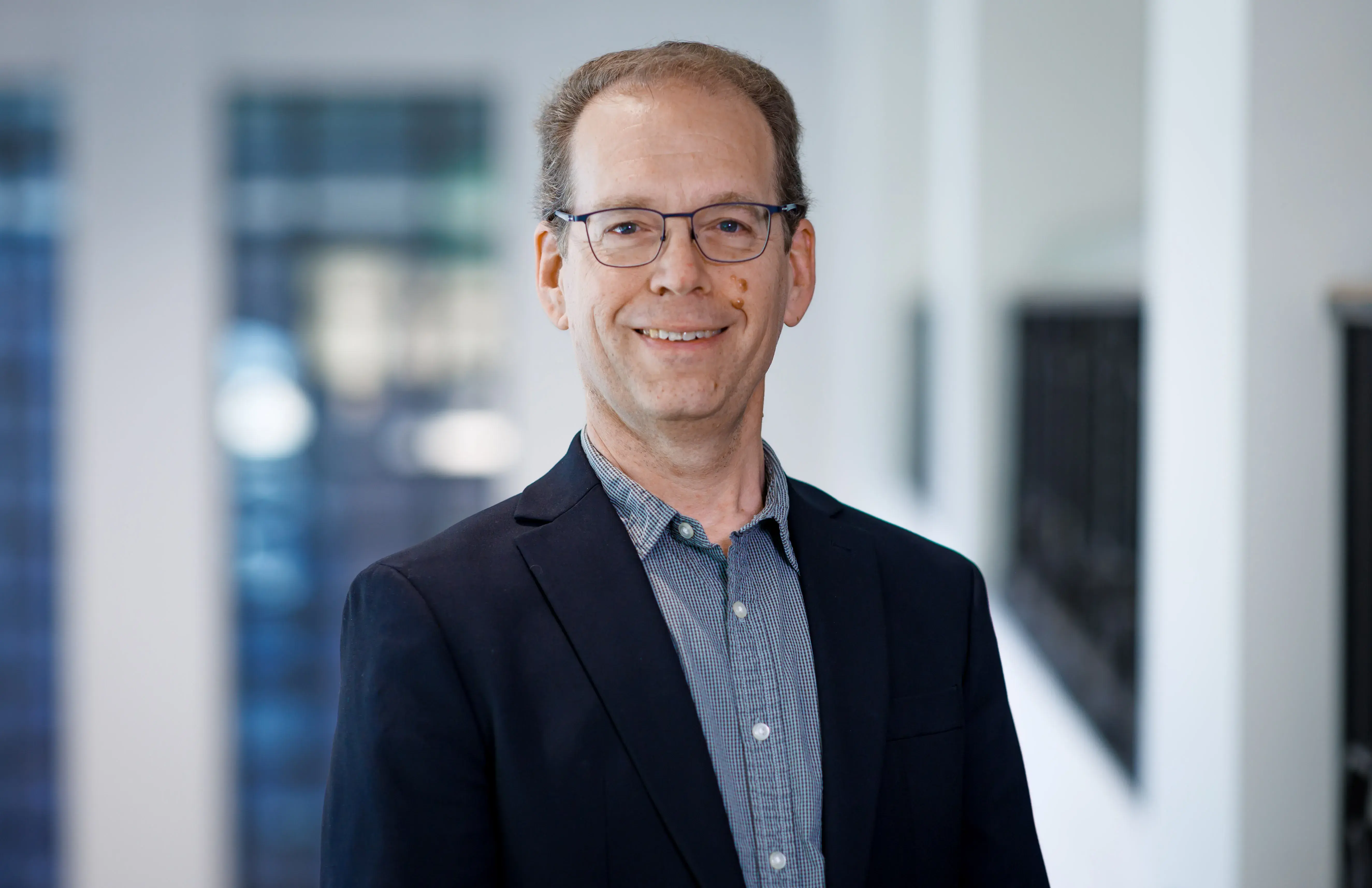 Steve Rankin posing for a headshot wearing a blue button down shirt and dark blue blazer